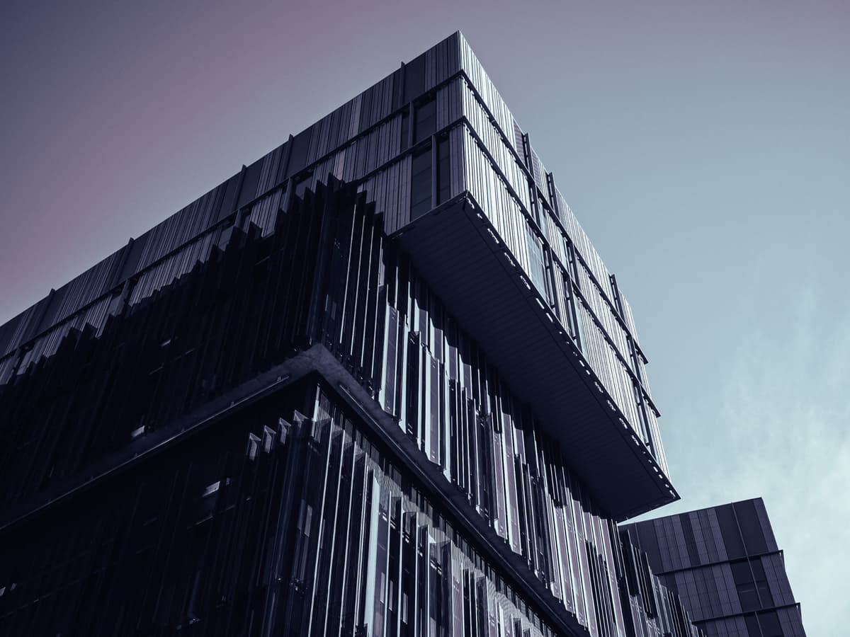 Modern corporate headquarters building with dark glass facade and geometric architecture representing professional corporate communication