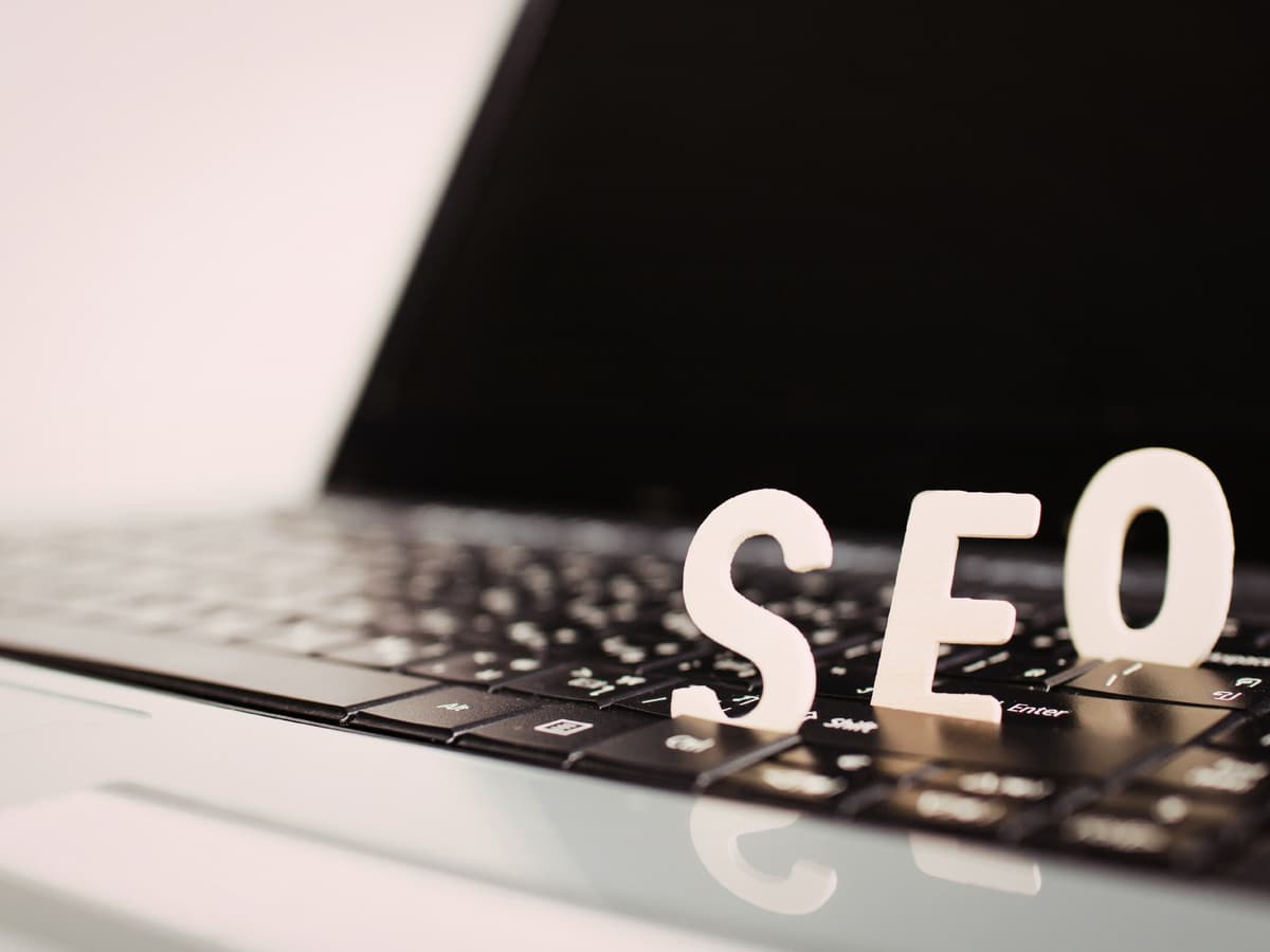 White 3D SEO letters on a laptop keyboard representing search engine optimization and digital communication trends