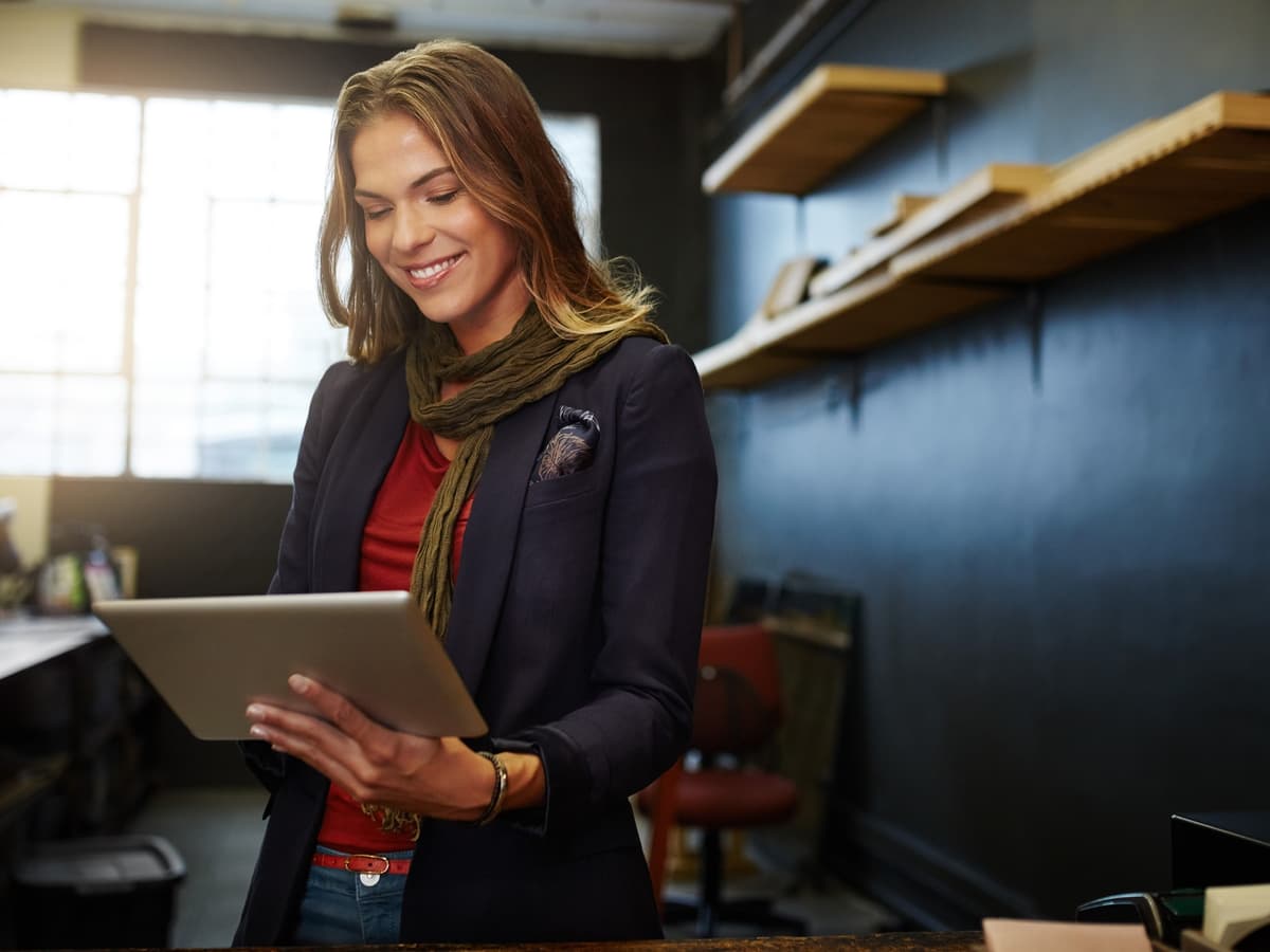 Professional businesswoman in navy blazer reviewing communication strategy on tablet in modern office setting